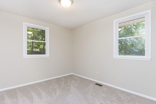 empty room with visible vents, a healthy amount of sunlight, baseboards, and carpet floors