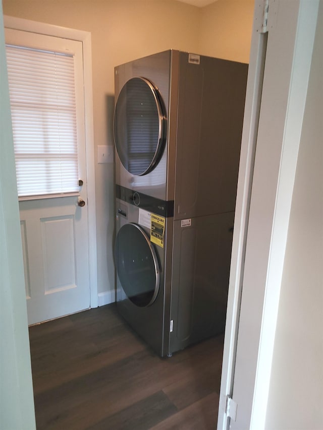 clothes washing area with stacked washer / drying machine and dark wood-type flooring