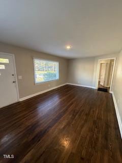 unfurnished living room with baseboards and dark wood-style floors