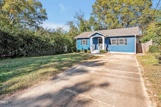 view of front facade featuring concrete driveway, a front lawn, and fence