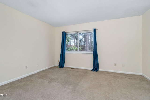 unfurnished room with visible vents, baseboards, light colored carpet, and a textured ceiling