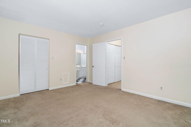 unfurnished bedroom with baseboards, carpet floors, and ensuite bath