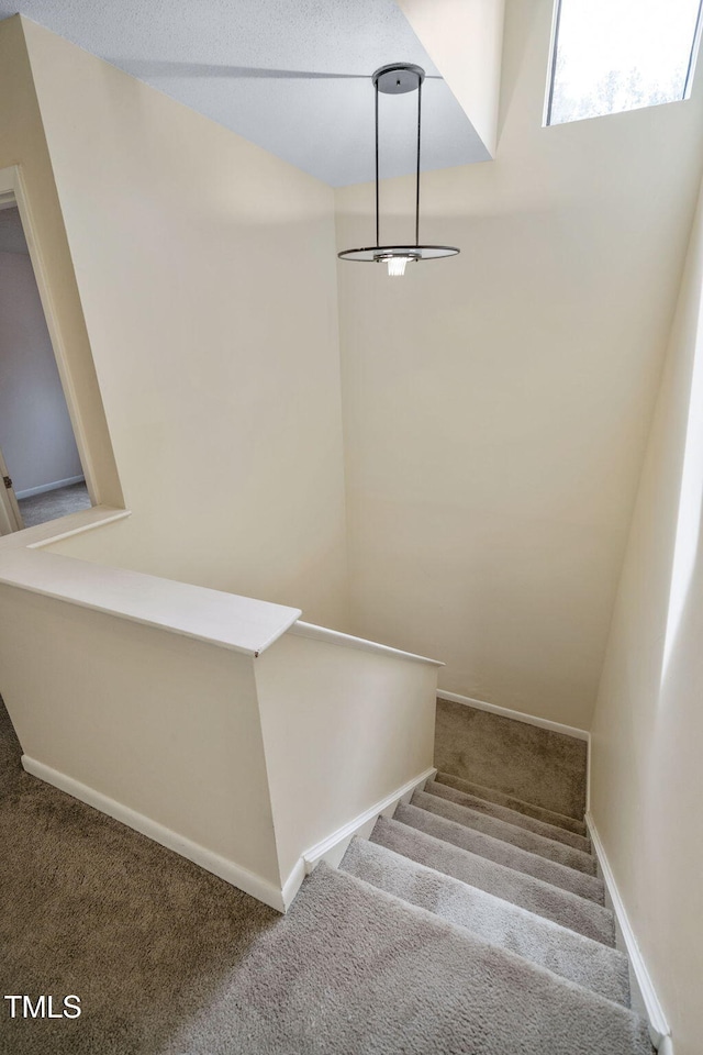 staircase featuring carpet flooring and baseboards