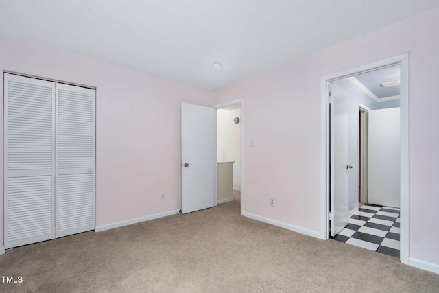 unfurnished bedroom featuring a closet, baseboards, ornamental molding, and carpet flooring