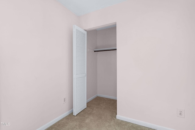 unfurnished bedroom featuring a closet, baseboards, and carpet