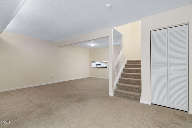 unfurnished living room with baseboards, light carpet, a textured ceiling, and stairs