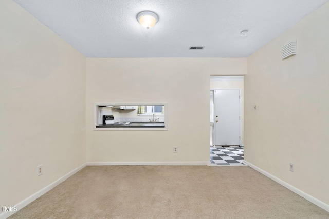 carpeted empty room with visible vents, a textured ceiling, and baseboards