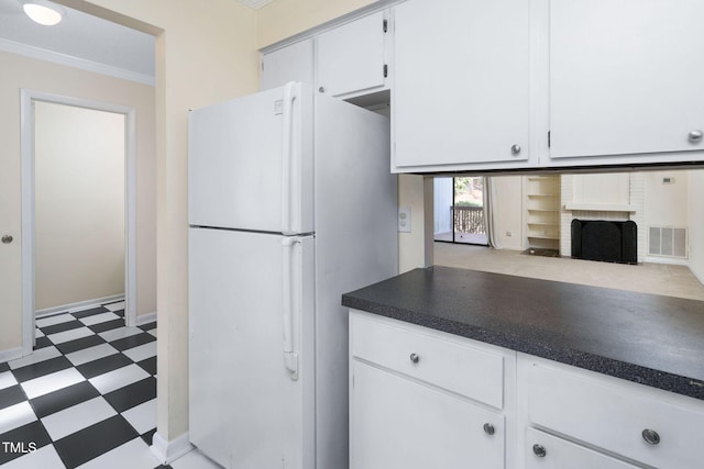 kitchen featuring visible vents, dark countertops, freestanding refrigerator, white cabinets, and light floors