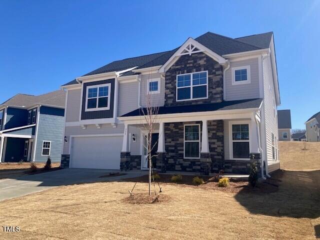 craftsman inspired home featuring a garage, stone siding, covered porch, and concrete driveway