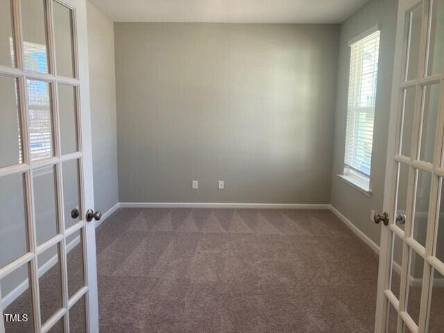 carpeted empty room featuring french doors and baseboards