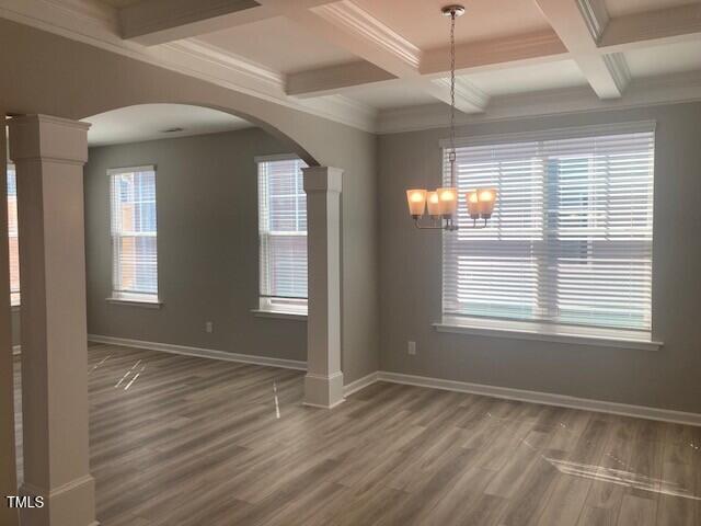 unfurnished dining area with baseboards, arched walkways, beam ceiling, and wood finished floors