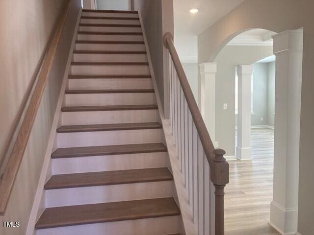 stairs featuring recessed lighting, wood finished floors, arched walkways, and ornate columns