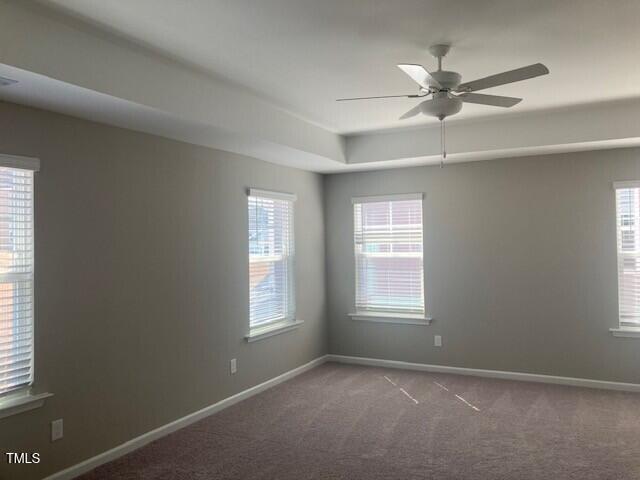 carpeted empty room featuring baseboards and ceiling fan