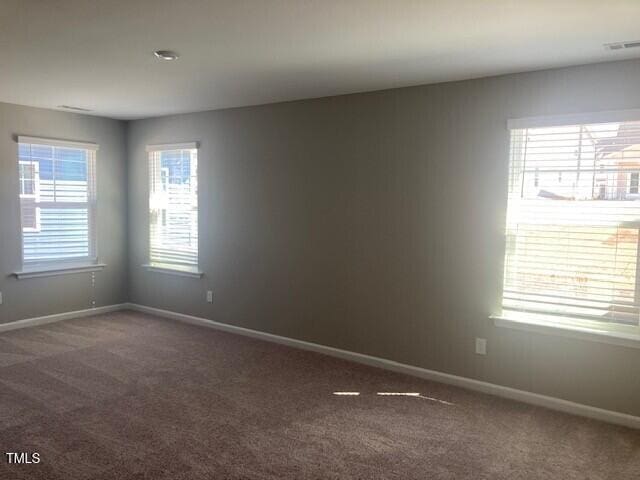 empty room featuring visible vents, baseboards, and carpet flooring