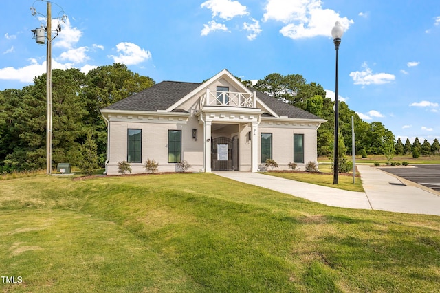 view of front of house with brick siding, a front yard, and a shingled roof