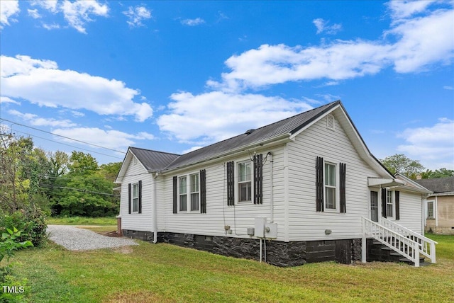 view of side of property featuring metal roof, a lawn, driveway, and crawl space