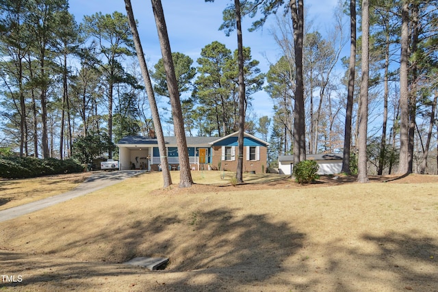 view of front facade with aphalt driveway, a front lawn, a carport, and brick siding