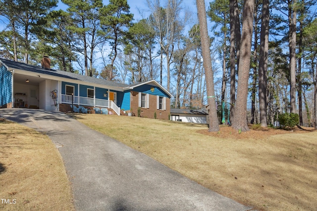 view of front of home with aphalt driveway, a porch, a front yard, a chimney, and a carport