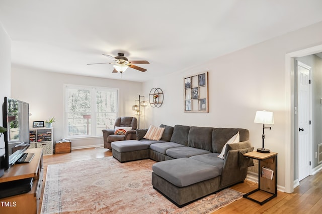 living area with baseboards, light wood-style floors, and ceiling fan