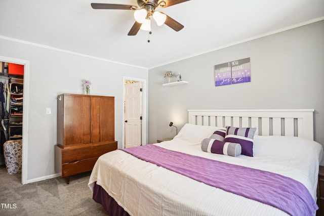 bedroom with a closet, carpet flooring, crown molding, baseboards, and a spacious closet