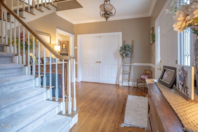 foyer entrance with baseboards, wood finished floors, stairs, and ornamental molding