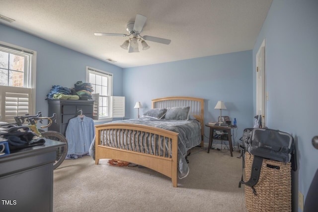 carpeted bedroom with visible vents, a textured ceiling, and ceiling fan