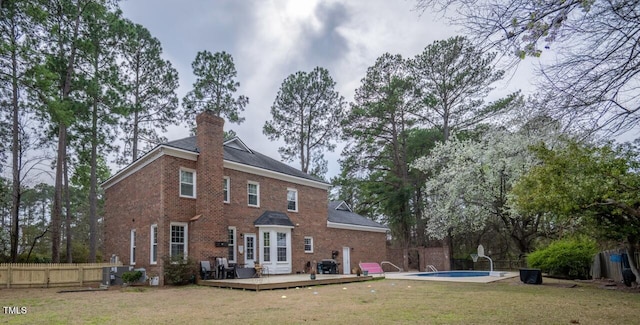 back of property with a lawn, a fenced in pool, a fenced backyard, and a wooden deck