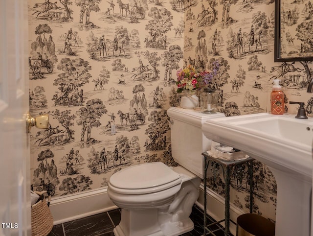 bathroom with a sink, toilet, and wallpapered walls