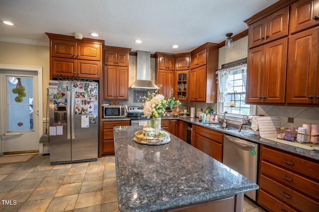 kitchen with brown cabinets, ornamental molding, tasteful backsplash, stainless steel appliances, and wall chimney range hood