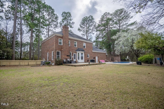 back of property with a deck, a fenced in pool, a lawn, and fence