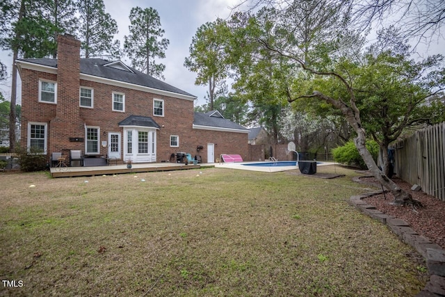 back of property featuring a deck, a fenced backyard, a fenced in pool, brick siding, and a chimney