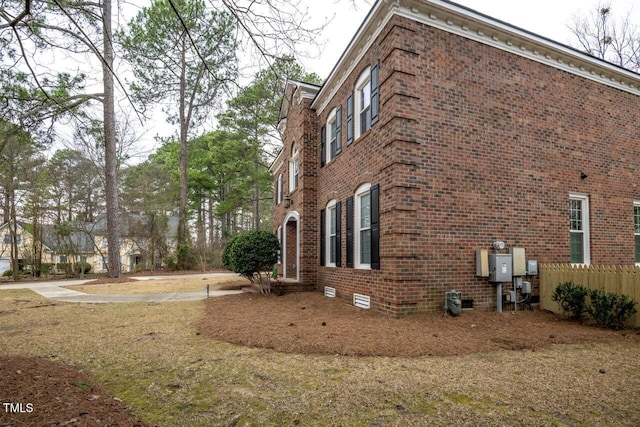 view of side of property featuring brick siding and fence