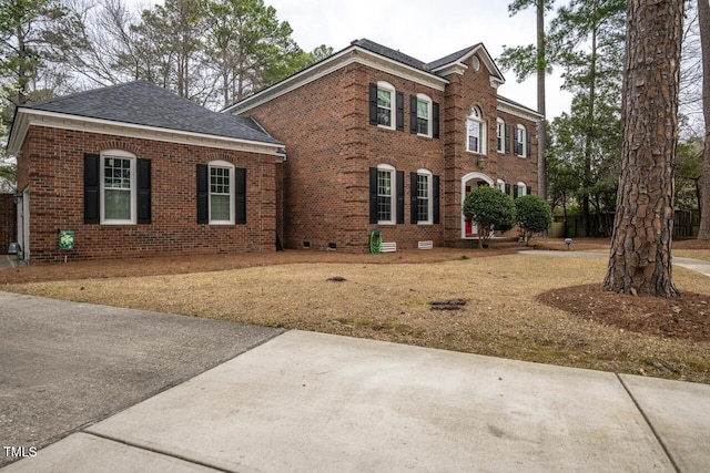 view of front of property featuring brick siding and roof with shingles