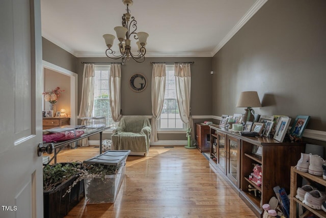 living area with ornamental molding, wood finished floors, baseboards, and a chandelier