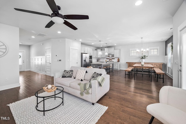 living room with visible vents, baseboards, recessed lighting, dark wood-type flooring, and ceiling fan with notable chandelier