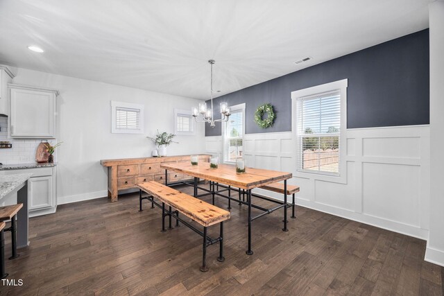 dining room featuring a wainscoted wall, an inviting chandelier, dark wood-style floors, and visible vents