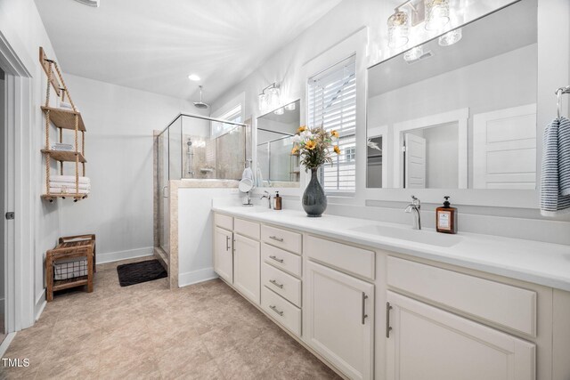 bathroom featuring double vanity, a shower stall, baseboards, and a sink