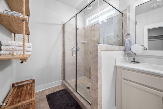 bathroom featuring vanity, a shower stall, and baseboards