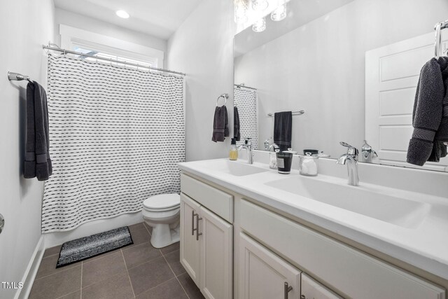 bathroom featuring tile patterned floors, toilet, a sink, shower / tub combo, and double vanity