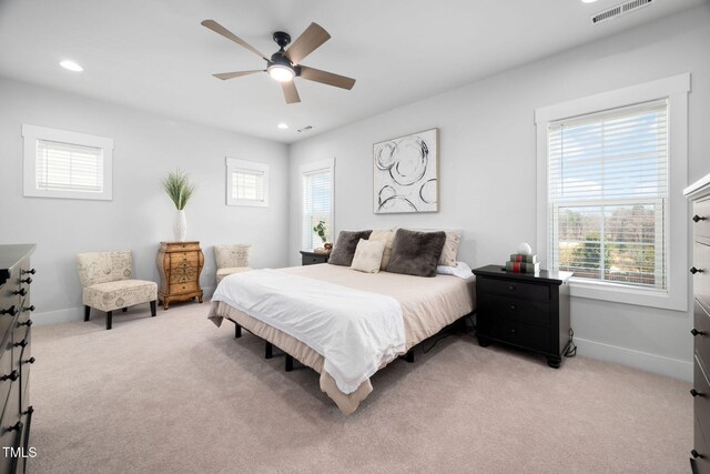 bedroom with visible vents, multiple windows, light colored carpet, and baseboards