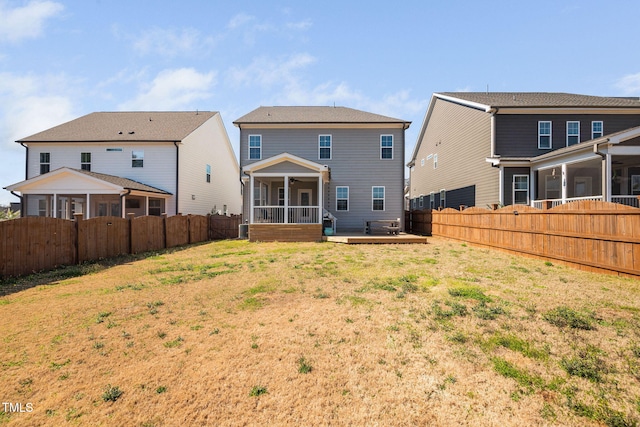 back of house featuring a yard, a deck, a fenced backyard, and a sunroom