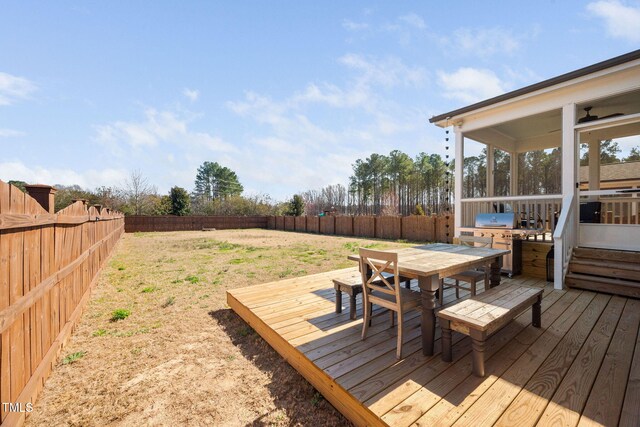 wooden terrace featuring grilling area, outdoor dining area, a fenced backyard, and a sunroom