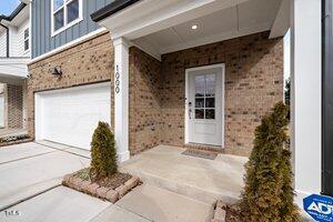 entrance to property with an attached garage, brick siding, board and batten siding, and driveway