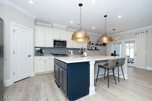 kitchen with decorative backsplash, stainless steel microwave, a large island, and crown molding