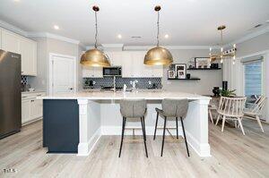 kitchen with a large island, stainless steel microwave, white cabinetry, freestanding refrigerator, and crown molding