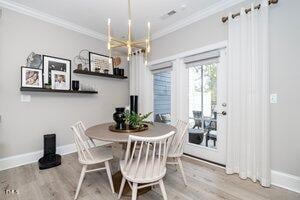 dining area featuring a notable chandelier, crown molding, baseboards, and wood finished floors