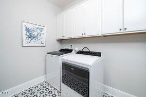 washroom featuring baseboards, cabinet space, and washer and clothes dryer