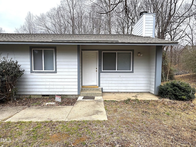 view of front facade featuring crawl space, entry steps, a chimney, and roof with shingles