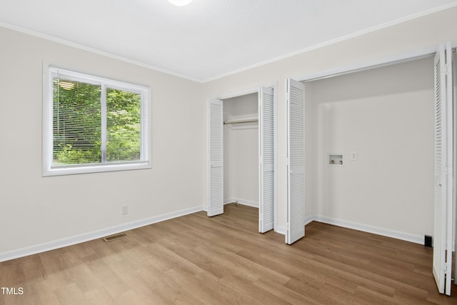 unfurnished bedroom featuring baseboards, visible vents, ornamental molding, and light wood-style floors