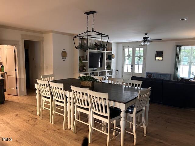 dining area with french doors, light wood-type flooring, ceiling fan, and ornamental molding